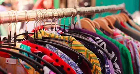 a lot of clothes hangers that are closely located next to each other in a  store with women's clothing, an atmosphere of women's space with a large  selection of colorful clothes Stock